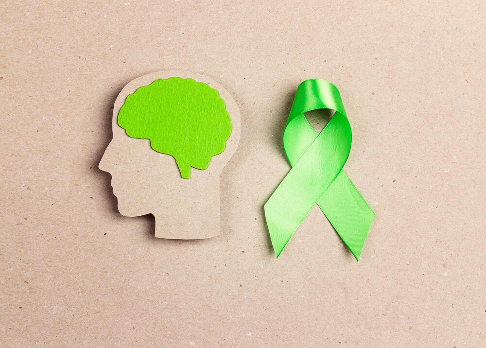 Mental health month green ribbon and brain diagram