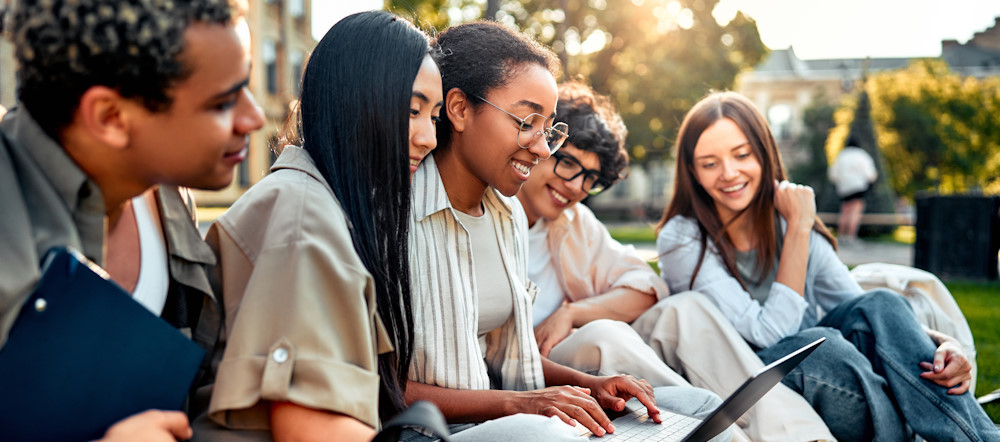 group of teens at school using a laptop